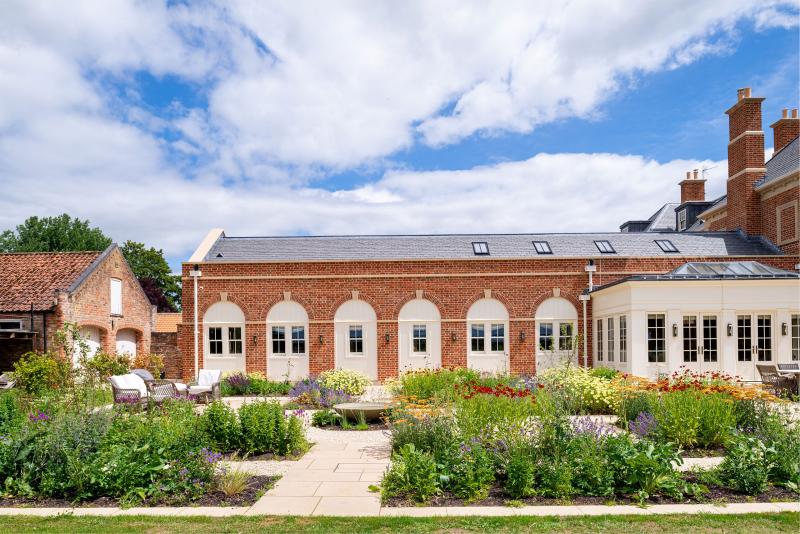 Red-brick country house with stone dressings, slate diminishing course roof and orangery