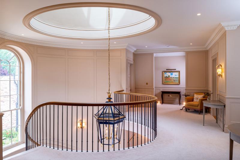 Landing with curved oak-topped staircase rail, oval ceiling dome and glimpse of a sitting room beyond
