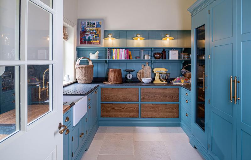 Blue-painted pantry with open shelving, cookbooks and a vintage yellow stand mixer
